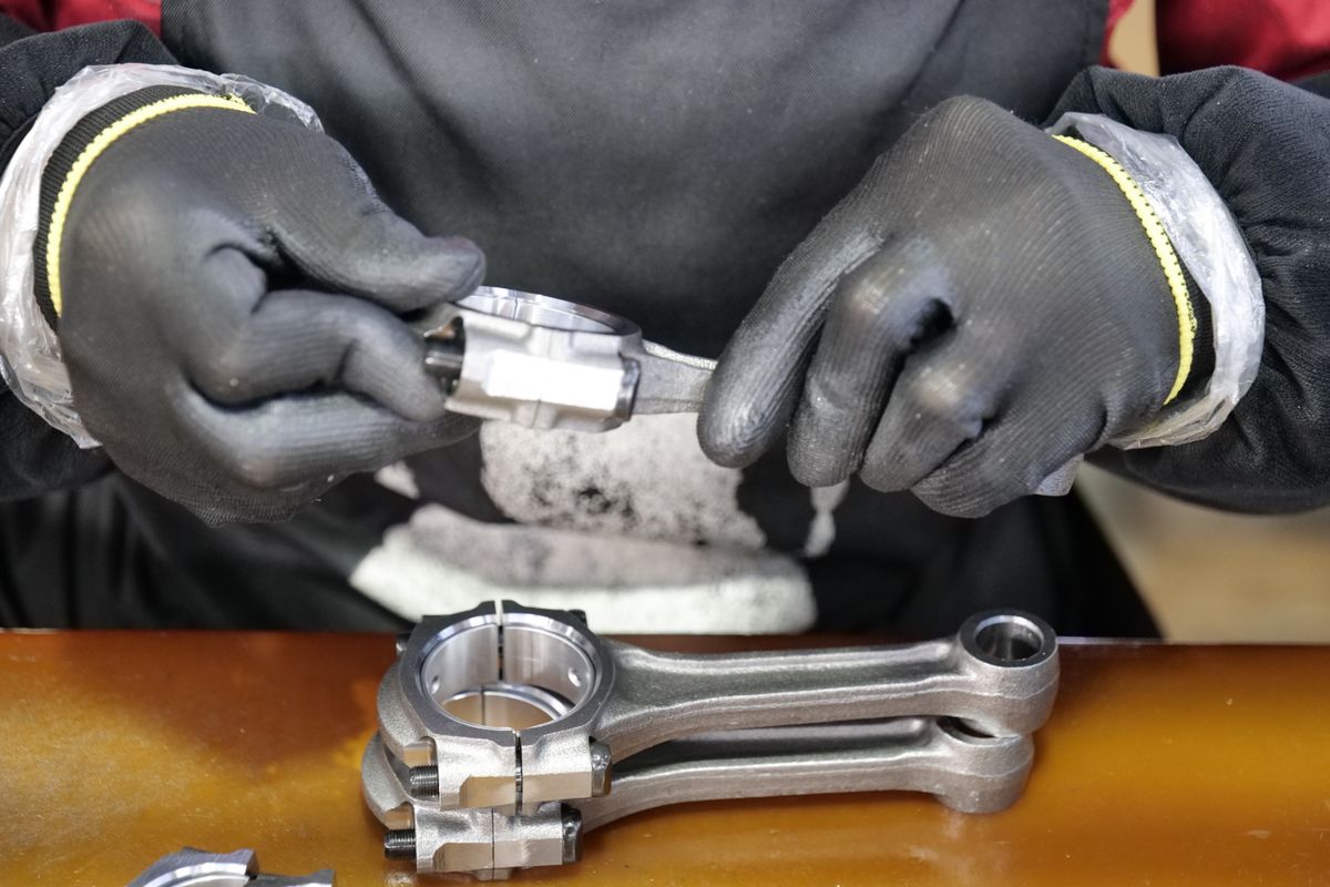 Behandschuhte Hände prüfen ein gefertigtes Metallbauteil